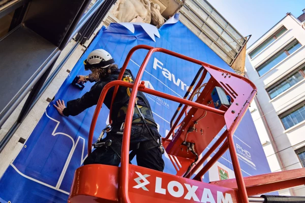 un homme en train d'installer une bâche sur un immmeuble