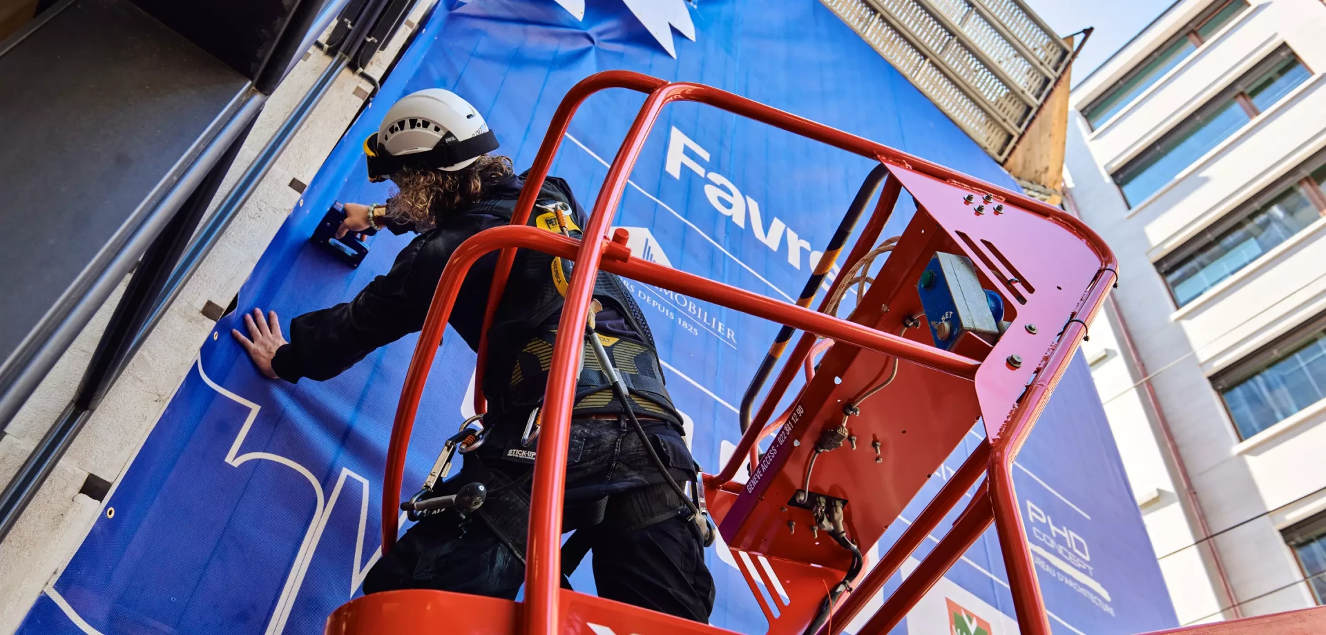 un homme en train d'installer une bâche d'immeuble