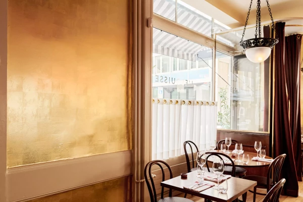 photo d'un intérieur de restaurant avec un mur recouvert de feuille d'or et des tables