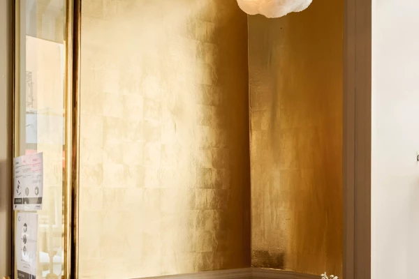 photo d'un intérieur de restaurant avec un mur recouvert de feuille d'or et un lampe