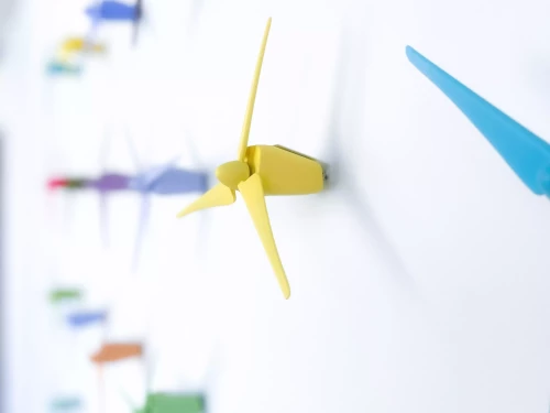 petites éoliennes de couleur contre un mur blanc