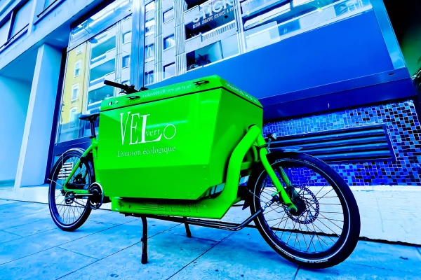 un vélo cargo customisé en vert et avec un logo de marque