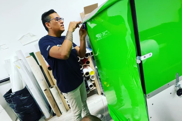 pose d'un vinyle adhésif publicitaire sur un vélo cargo vert