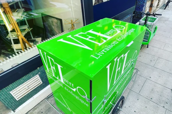 un vinyle adhésif publicitaire sur un vélo cargo vert