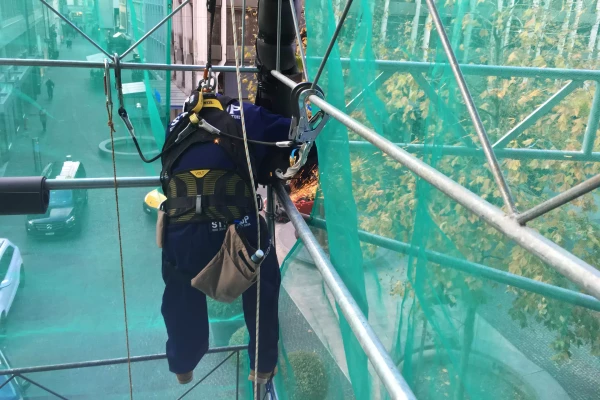 un ouvrier accrochant une bâche de chantier