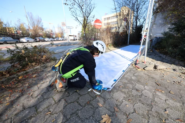 un ouvrier en train de poser une bâche publicitaire