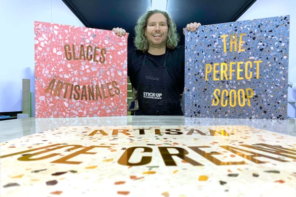 une personne présentant 2 plaques de terrazzo gravées