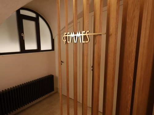 lettres en laition indiquant femme à l'entrée des wc