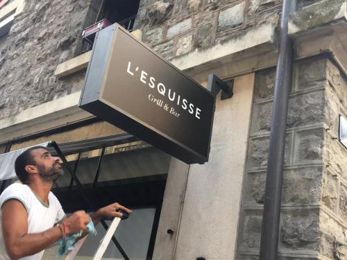 pose par un homme d'une enseigne publicitaire mural sur une façade d'immeuble
