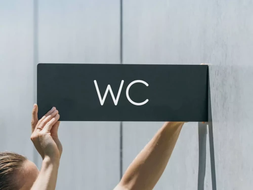 pose d'une enseigne de wc mural sur une façade d'immeuble